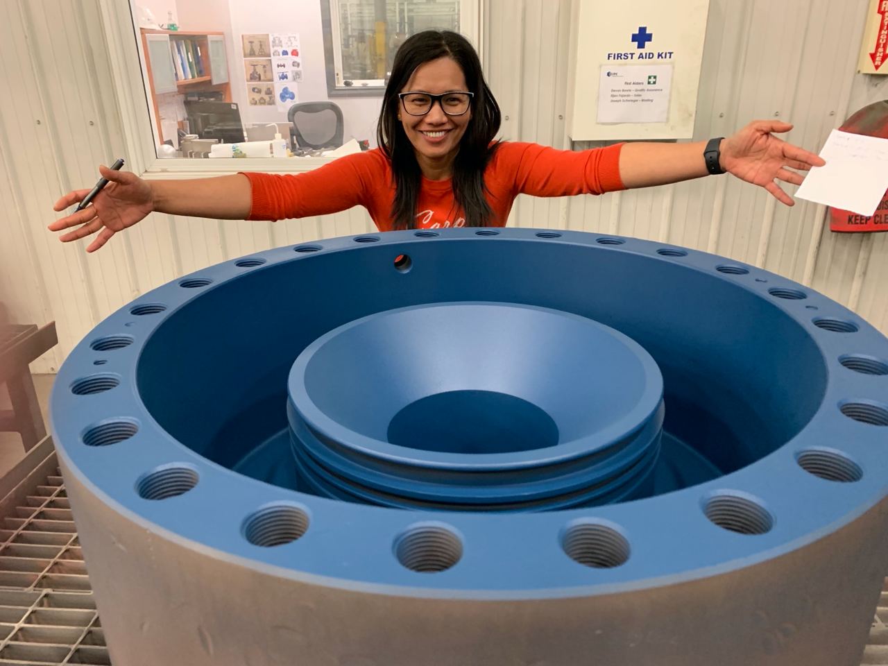 IPC employee standing over wellhead part coated in an IPC protective coating product