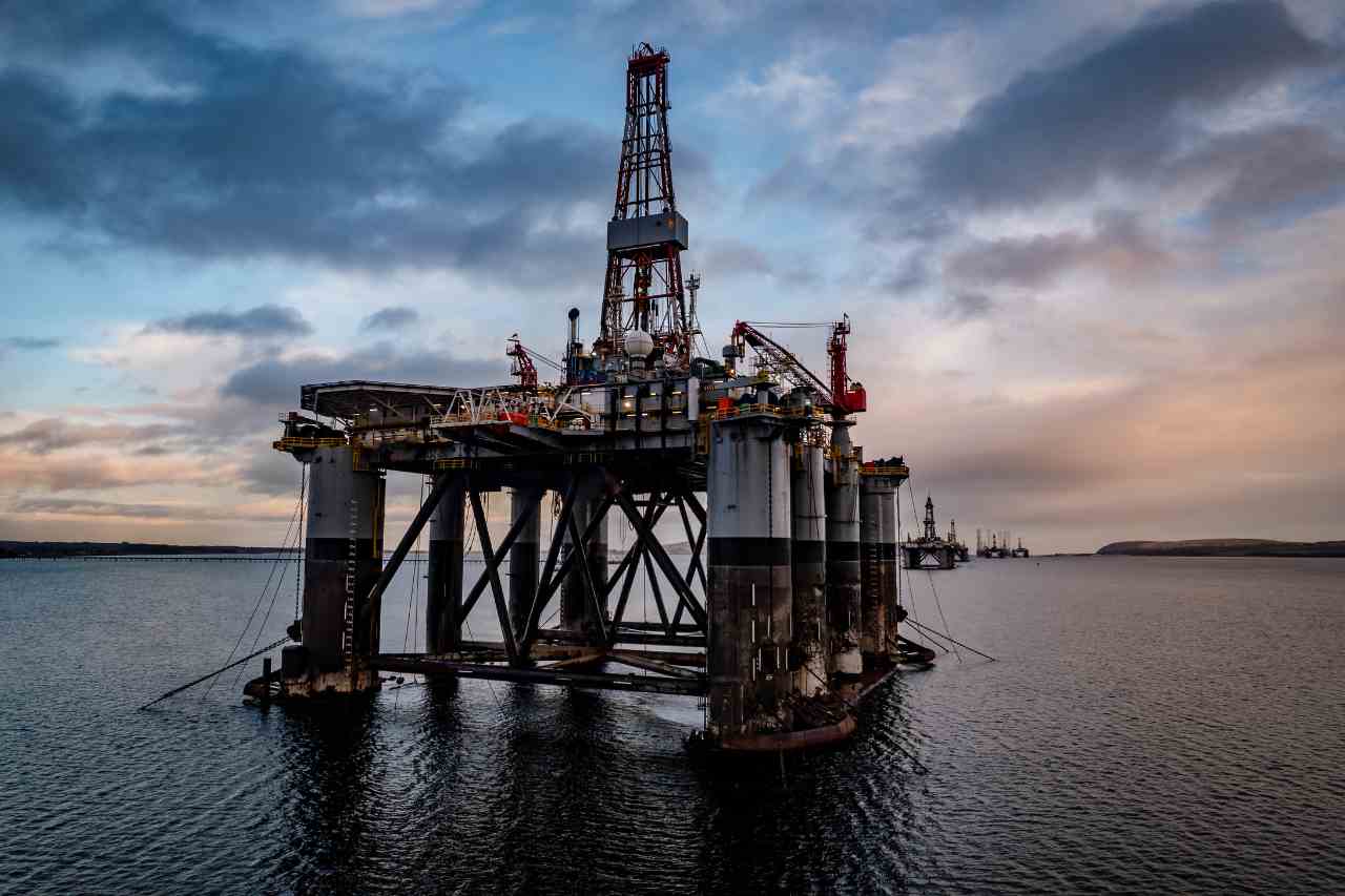 A large oil rig plant at sea in front of a sunset.