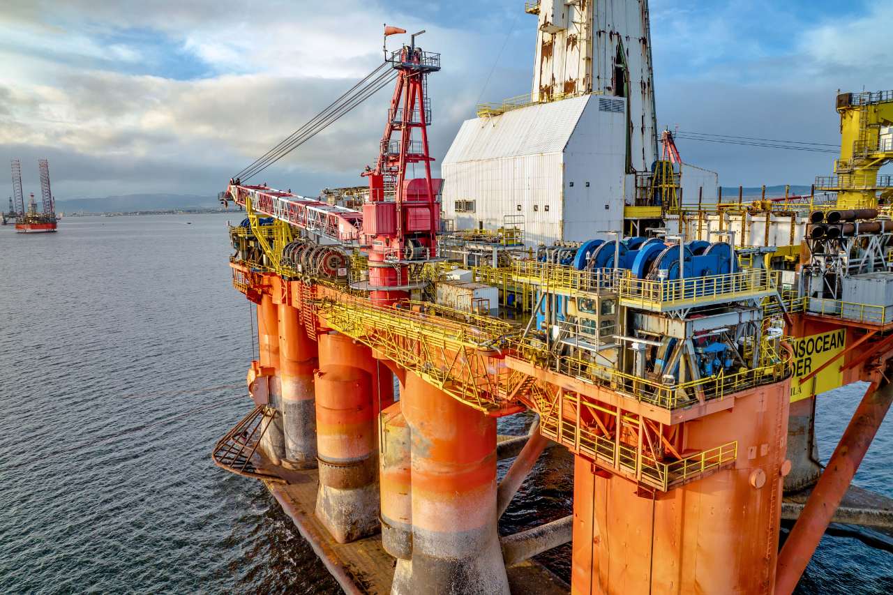 An off-shore oil rig floating on the ocean, with bright orange beams.