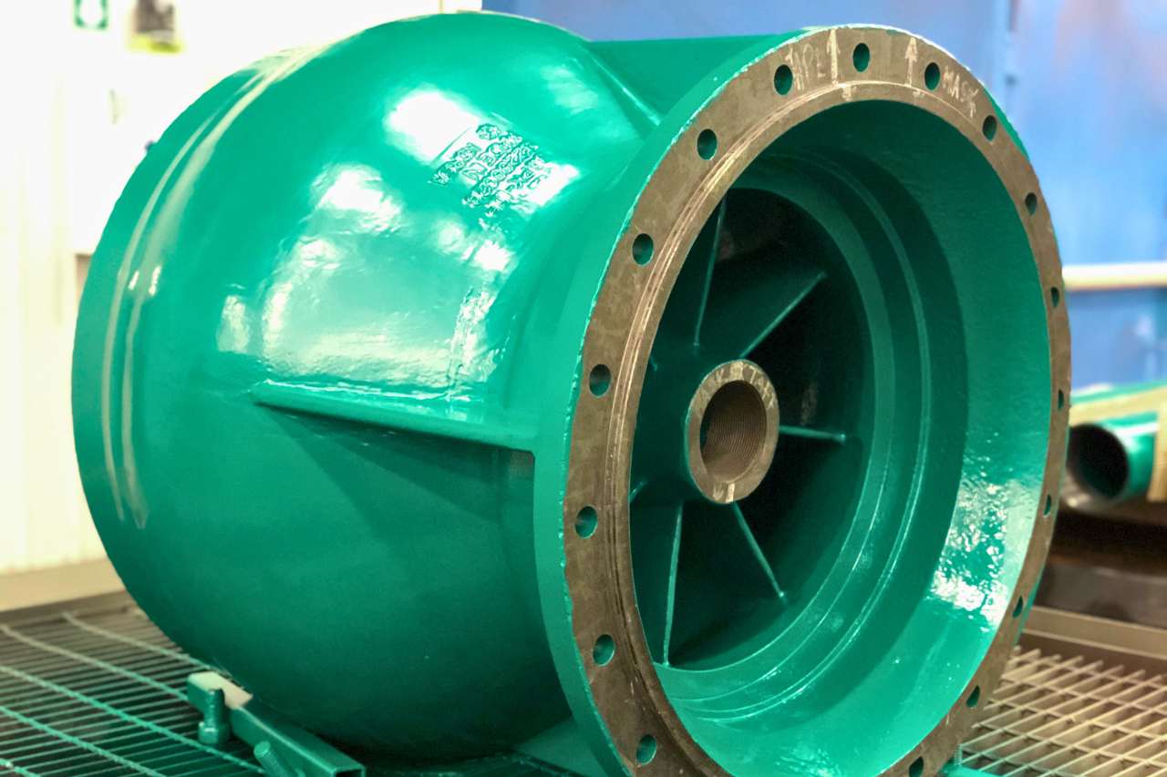 A large, round piece of industrial equipment has been covered in a green protective coating to prevent corrosion.