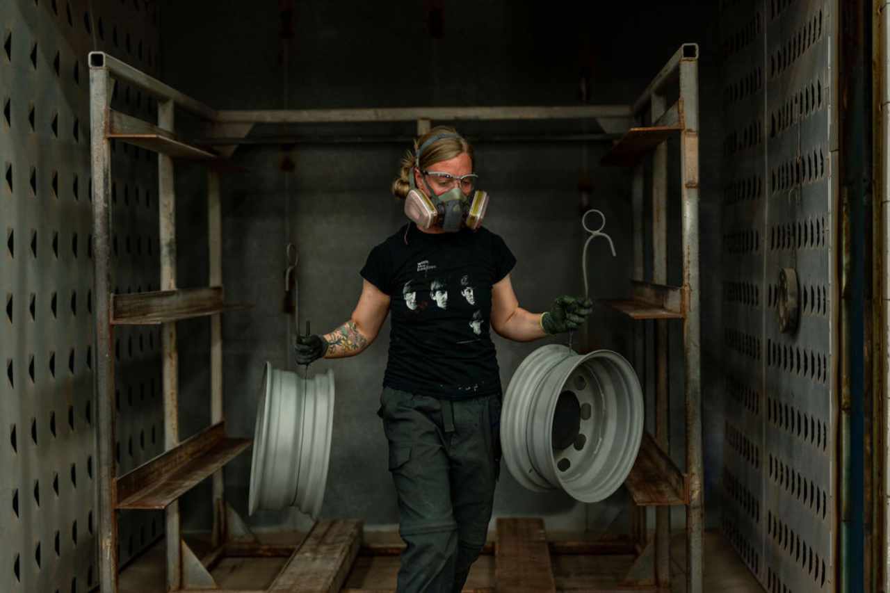 A female technician removes tire rims from one of the curing ovens.